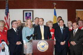 Leg. Rob Calarco at the podium discusses passage of his bill, IR 2025, requiring county roadways to be designed to accommodate all users. (left to right) Legislators Wayne Horsley and Kara Hahn (a co-sponsor of the bill); Leg. Calarco, Will Stoner of the AARP; Leg. Ricardo Montano. (Rear left to right) Eric Alexander of Vision Long Island; Sal Russo, 2nd vice president of SCAME; and Leg. William (Doc) Spencer. 